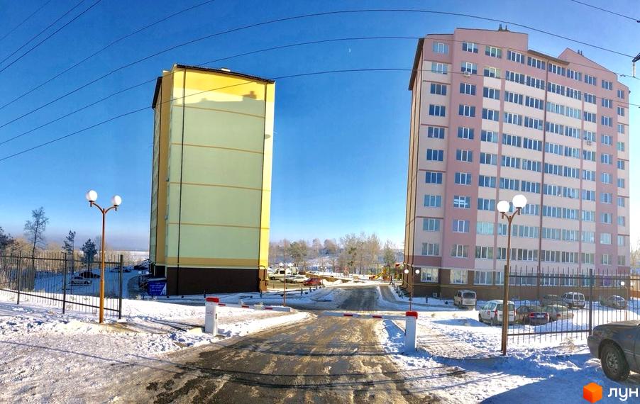 Зовнішній вигляд новобудови ЖК 4 Карата взимку. Навколо будинку розташована прибудинкова територія з дорогою та ліхтарями.