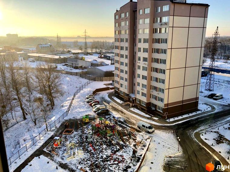 Житловий комплекс 4 Карата з фасадом у світлих тонах та прибудинковою територією із зимовим ландшафтом та дитячим майданчиком.