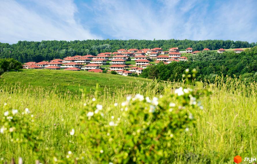 Комплекс КМ Маєток. Перлина Італії розташований на зеленому схилі, оточений природою, з котеджами з червоними дахами.