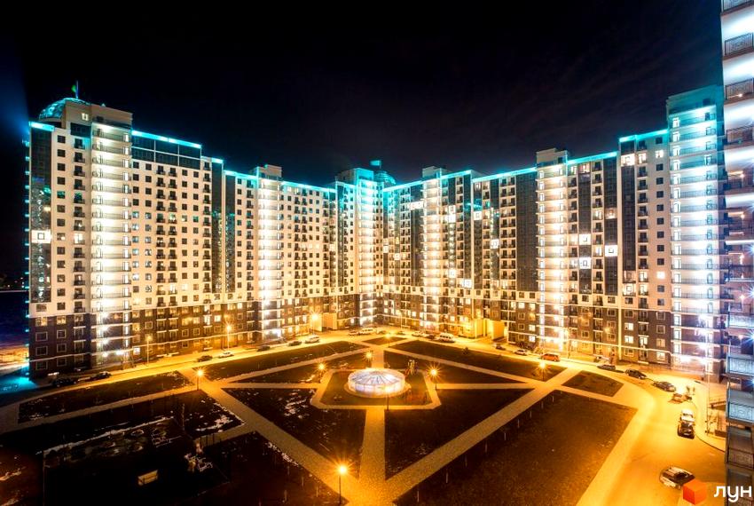 Житловий комплекс Пятая Жемчужина вночі, освітлені фасади будинків та прибудинкова територія з фонтаном.