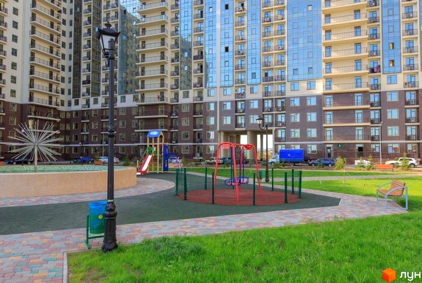 Житловий комплекс Пятая Жемчужина. Багатоповерхові будинки з балконами та скляними фасадами. Прибудинкова територія з дитячим майданчиком, гойдалками та лавками.
