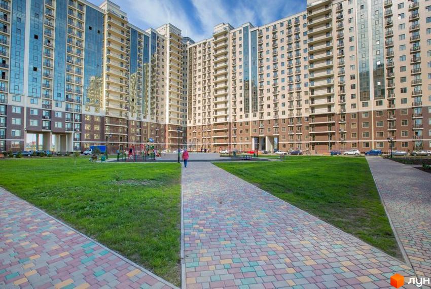 Житловий комплекс Пятая Жемчужина. Багатоповерховий будинок з панорамним склінням та балконами. Прибудинкова територія з дитячим майданчиком та зеленими зонами.