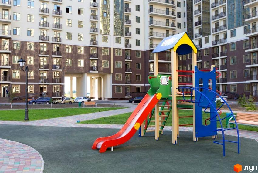 Житловий комплекс ЖК Пятая Жемчужина. Дитячий майданчик з гіркою та лазанкою на тлі багатоповерхових будинків.