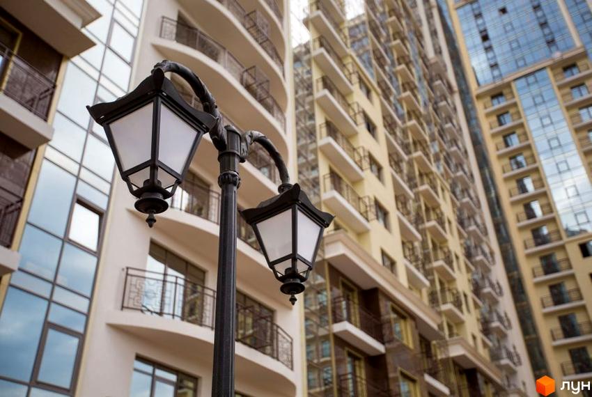 Житловий комплекс Восьма Перлина з сучасними фасадами та балконами. Зовнішній вигляд новобудови та вуличного ліхтаря.