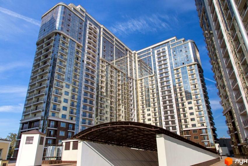 Житловий комплекс Восьма Перлина - висотна новобудова з балконами та скляними фасадами. На передньому плані навіс для автомобілів.