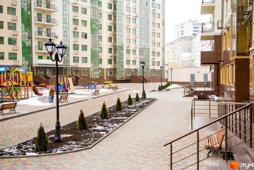 Зображення фасаду та прибудинкової території Житлового комплексу Десята Перлина. Вигляд на дитячий майданчик та пішохідну зону.