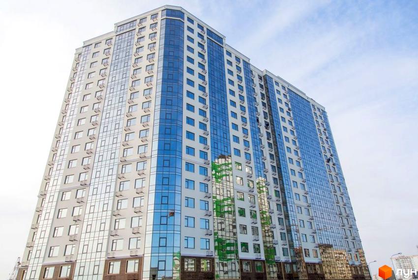 Зображення багатоповерхового будинку Житлового комплексу Десята Перлина з великими вікнами. Вигляд фасаду та прилеглої території.