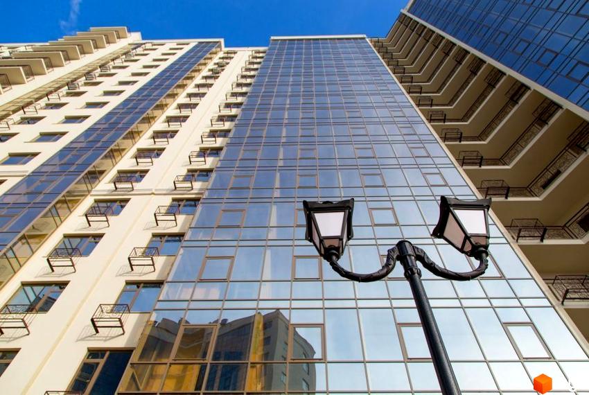 Вигляд на висотний будинок з великими вікнами Житловий комплекс Десята Перлина. На передньому плані ліхтар.