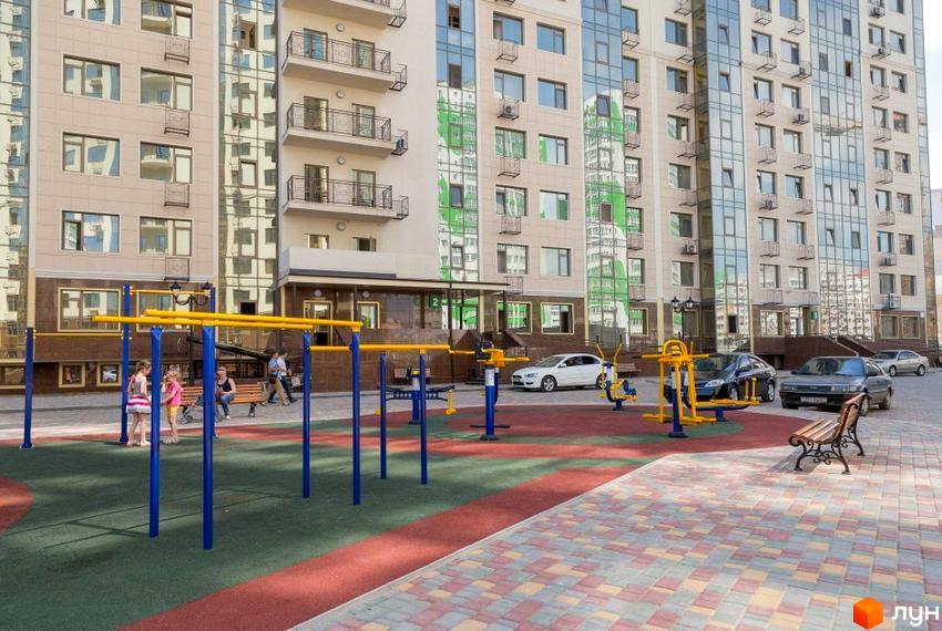 Зовнішній вигляд багатоповерхового будинку в Житловому комплексі Десята Перлина. На прибудинковій території дитячий майданчик та місця для відпочинку.