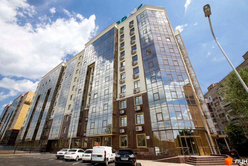 Зовнішній вигляд багатоповерхового будинку в Житловому комплексі Одинадцята Перлина з великими вікнами. На передньому плані припарковані автомобілі.