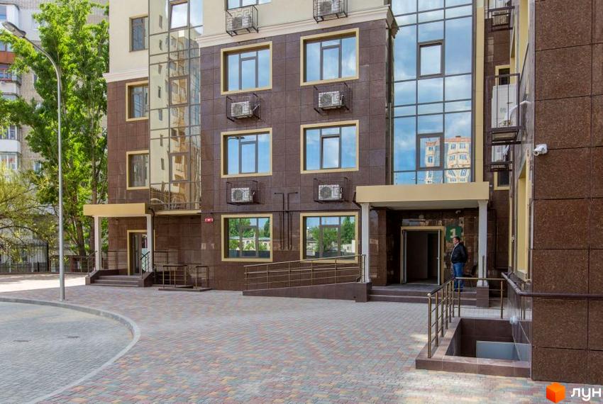 Зовнішній вигляд будинку в Житловому комплексі Одинадцята Перлина. Фасад з вікнами та кондиціонерами, вхідна група та прибудинкова територія.