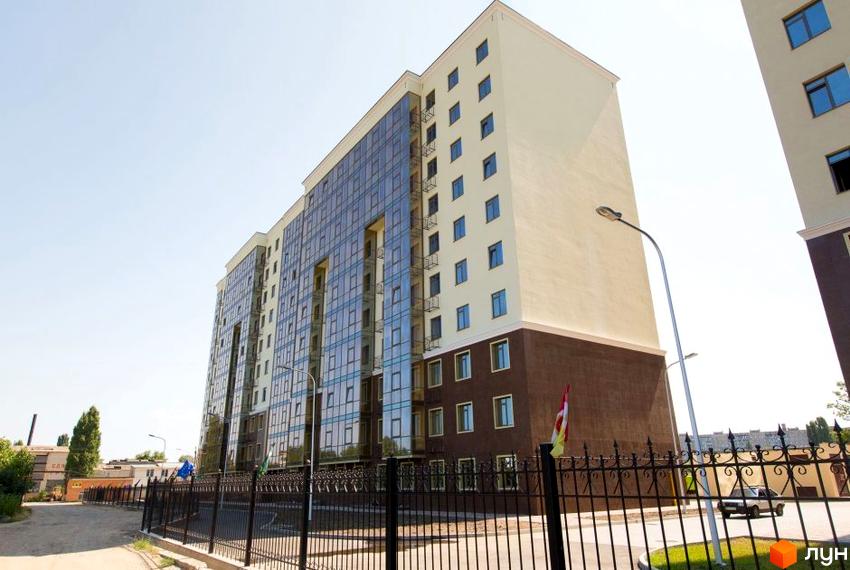 Зовнішній вигляд багатоповерхового будинку в Житловому комплексі Дванадцята Перлина. На передньому плані огорожа та прибудинкова територія.