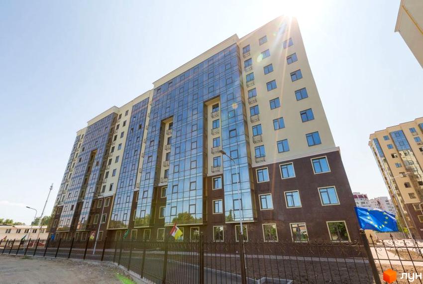 Зображення фасаду Житлового комплексу Дванадцята Перлина. Багатоповерхова будівля з великими вікнами та прапорами на передньому плані.