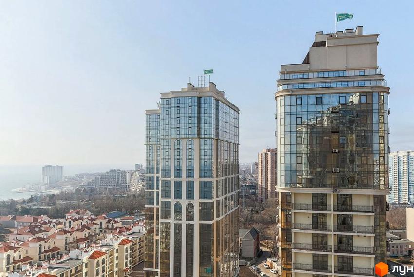 Житловий комплекс Дев'ятнадцята перлина. Високі будинки з скляними фасадами та прапорами на дахах. Навколо розташовані інші будівлі та зелені насадження.