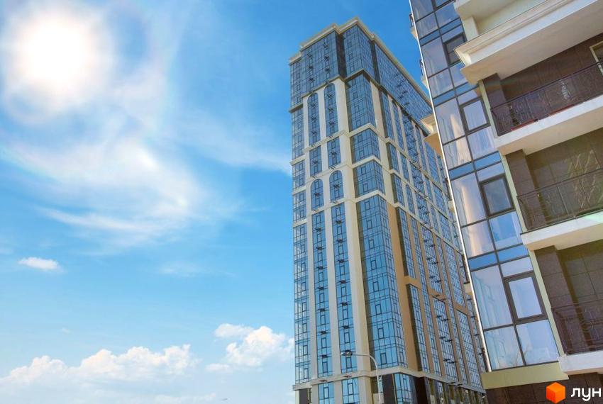 Висотна будівля ЖК Дев'ятнадцята перлина з скляними вікнами на тлі блакитного неба. Архітектура будівлі поєднує світлі фасади та великі вікна, що створює відчуття простору.