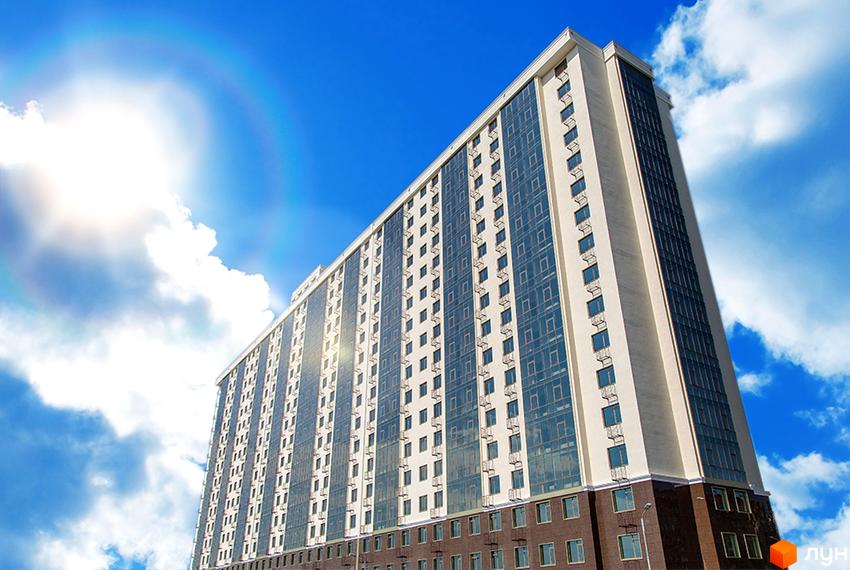 Житловий комплекс Двадцята Перлина: високий багатоповерховий будинок з бежевим фасадом, великими скляними вікнами та темною основою.