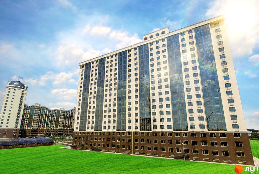 Житловий комплекс Двадцять перша Перлина: багатоповерховий будинок зі світлими та скляними секціями, а також коричневим цоколем. Перед будинком розкинувся зелений газон.