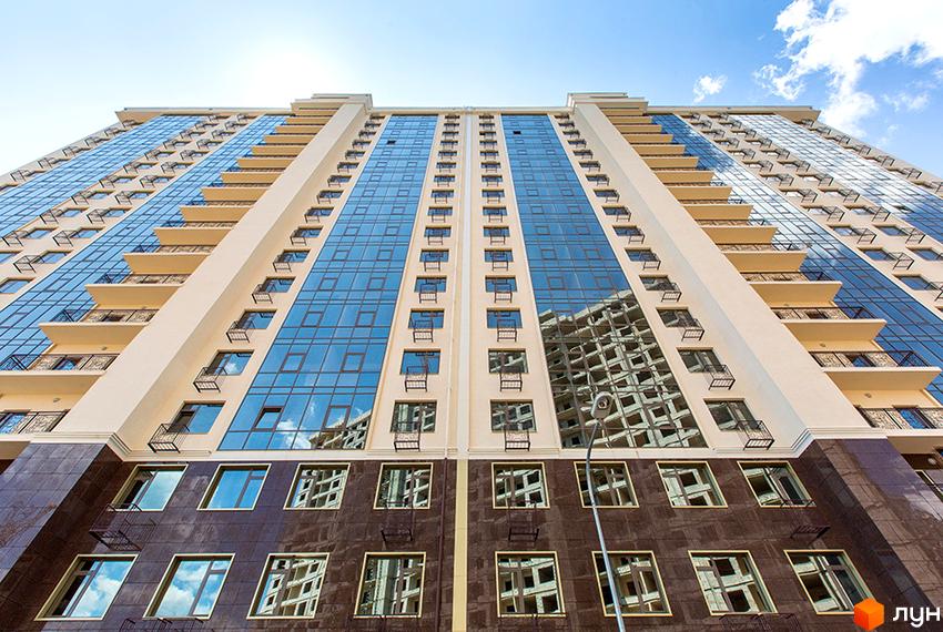 Житловий комплекс Двадцять перша Перлина: висотна будівля зі скляними фасадами, балконами та темною основою під ясним небом.