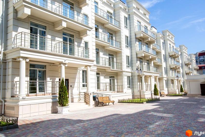 Зображення фасаду Житлового комплексу Двадцять восьма перлина з балконами. На передньому плані прибудинкова територія з лавками та озелененням.
