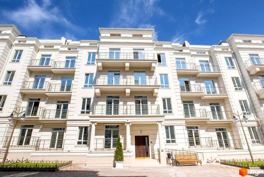 Зображення фасаду Житлового комплексу Двадцять восьма перлина. Багатоповерховий будинок з балконами та великими вікнами, перед будинком зелена зона з лавкою.