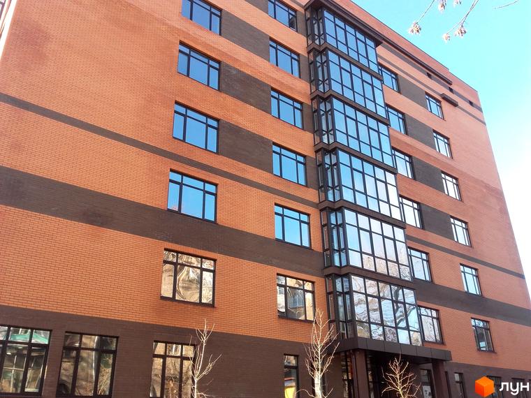 Зовнішній вигляд новобудови ЖК Palladio: цегляний фасад з темними смугами та великими вікнами. Будинок має багатоповерхову структуру з скляним еркером.