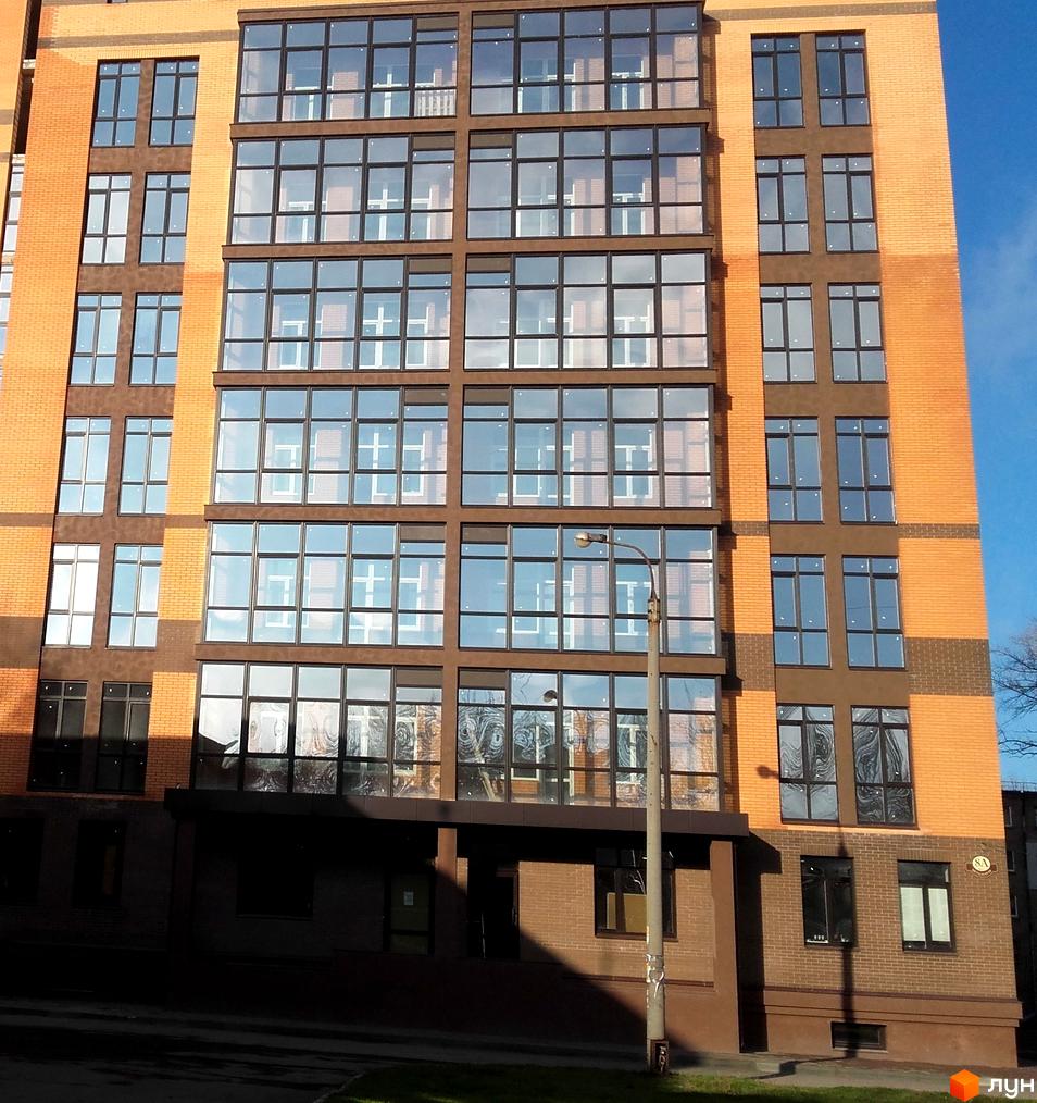 Житловий комплекс Palladio: фасади будівель з великою кількістю скління та цегляним оздобленням. Поруч розташована вулиця та зелені насадження.