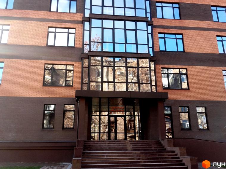 Зовнішній вигляд новобудови ЖК Palladio з цегляним фасадом та великими вікнами. Вхідна група з сходами та скляним оздобленням.