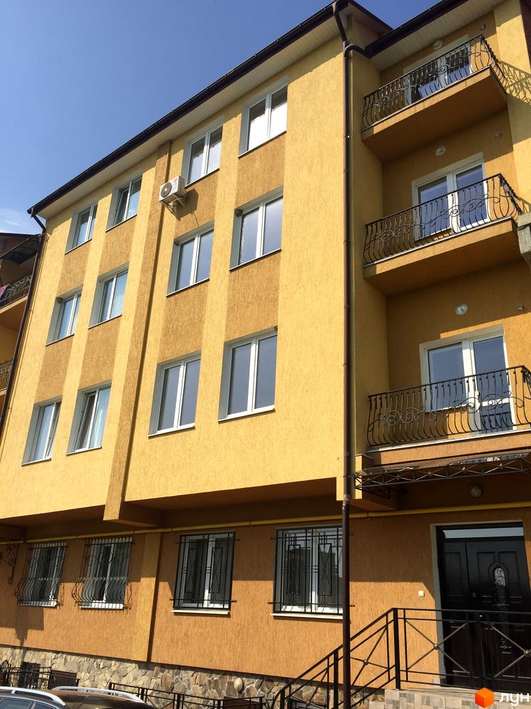 Фасад житлового комплексу на вулиці Воробкевича. Будинок має жовтий колір, балкони з кованою огорожею та великі вікна. Біля будинку розташовані сходи та вхідні двері.