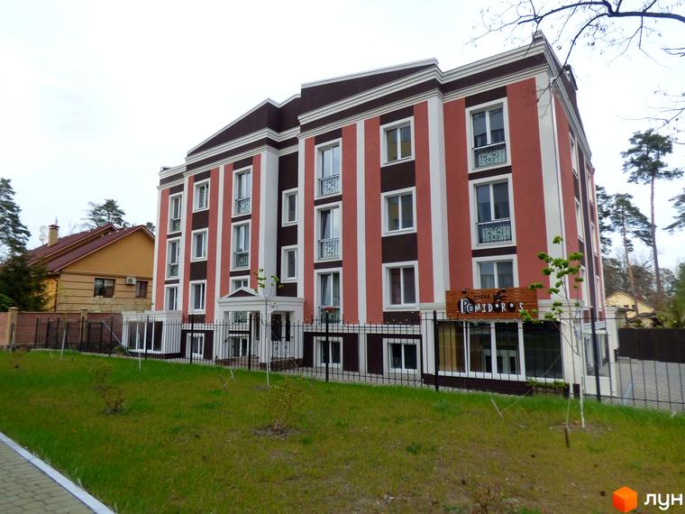 Сучасна новобудова на вулиці Антонія Михайлівського з червоно-білими фасадами та коричневими елементами. Прибудинкова територія доглянута, з газоном та огорожею.