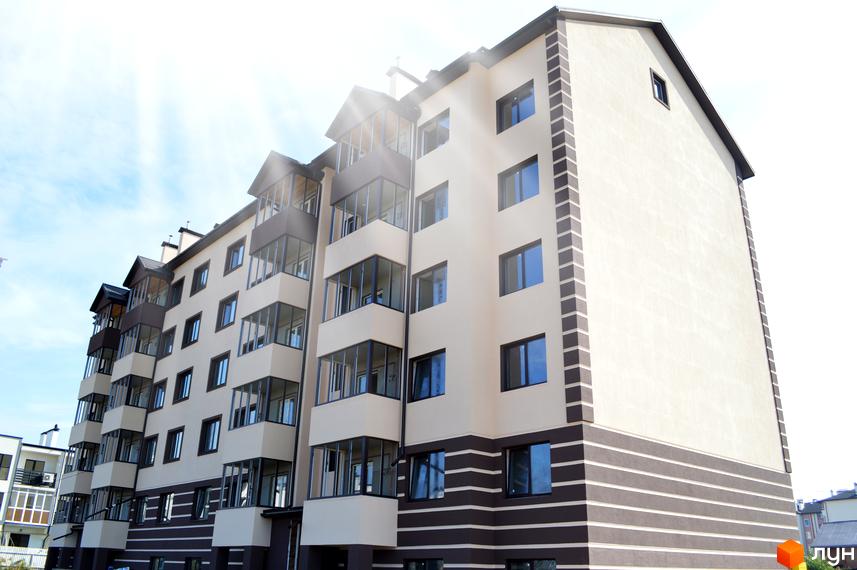 Житловий комплекс Сонячний: багатоповерховий будинок кремового кольору з темно-коричневим цоколем та заскленими балконами.