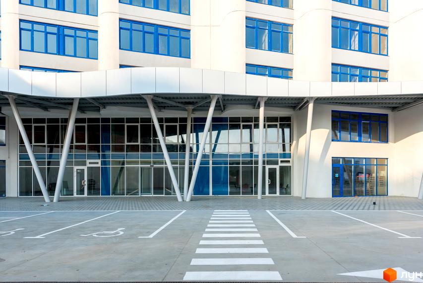 Фасад житлового комплексу Морська симфонія з великими вікнами та сучасним входом. Прибудинкова територія з паркувальними місцями та пішохідними доріжками.