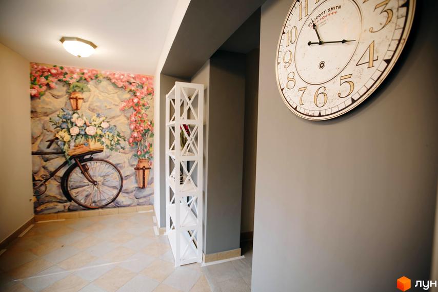 Житловий комплекс Comfort Club: стильний інтер'єр холу з картиною та годинником. Опис дизайну та оздоблення приміщень.