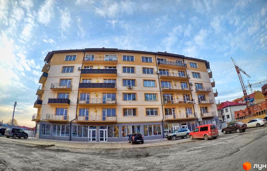 Житловий комплекс Климпуша – це багатоповерхова новобудова з балконами та великими вікнами. Перед будинком розташована прибудинкова територія з автомобілями та дорогою.