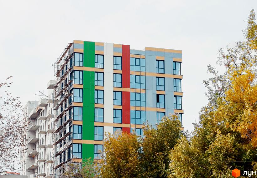 Новобудова Palermo: багатоповерховий будинок з кольоровим фасадом та риштуваннями, оточений осінніми деревами.