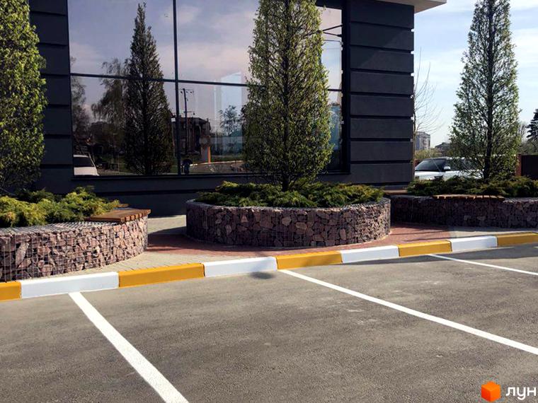 Зовнішній вигляд будівлі житлового комплексу Continent з великими вікнами. На прибудинковій території розташовані клумби з рослинами та паркувальні місця.