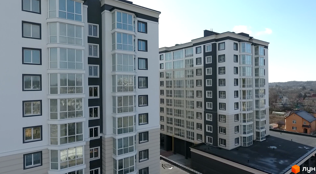 Високоповерхові будинки ЖК Continent з панорамними вікнами. Білі фасади з темними акцентами та великі скляні балкони.