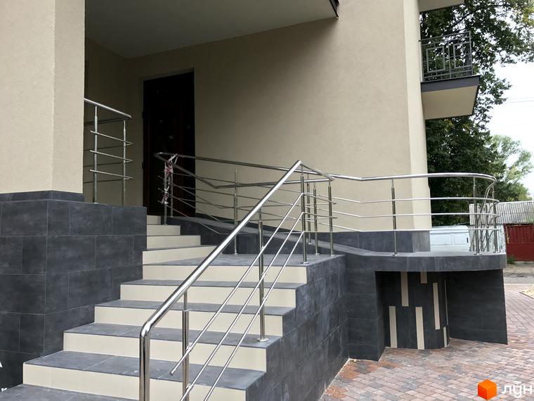 Вхідна група житлового комплексу Brownie House з сходами та металевими поручнями. На території комплексу плитка та зелені насадження.
