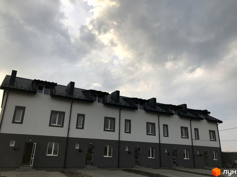 Зображення таунхаусів HarmonyBud. Двоповерхові будинки з сірими дахами та білими стінами, частина яких пофарбована в сірий колір.