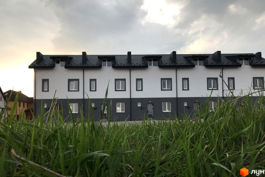 Фото таунхаусів HarmonyBud з сірими дахами та білими стінами. Перед будинками зелений газон.