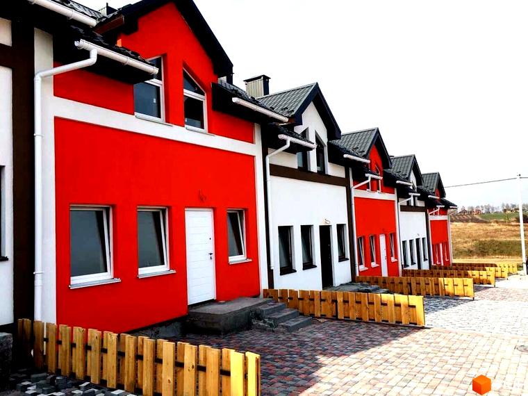 Зображення таунхаусів у Житловому комплексі Grass House. Двоповерхові будинки з червоними та білими стінами, темними дахами та дерев'яними парканами.