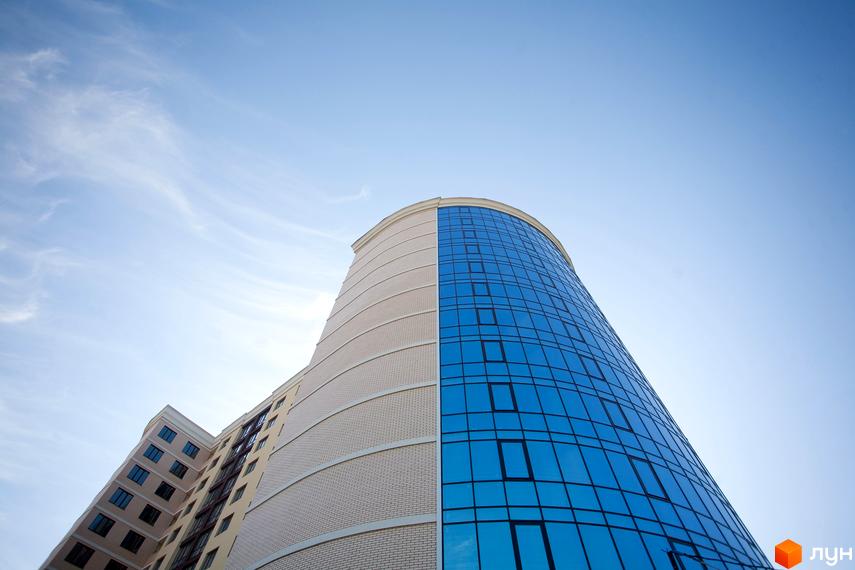 Зображення фасаду Новобудови Paradise з великими вікнами. Вигляд знизу вгору на багатоповерховий будинок.