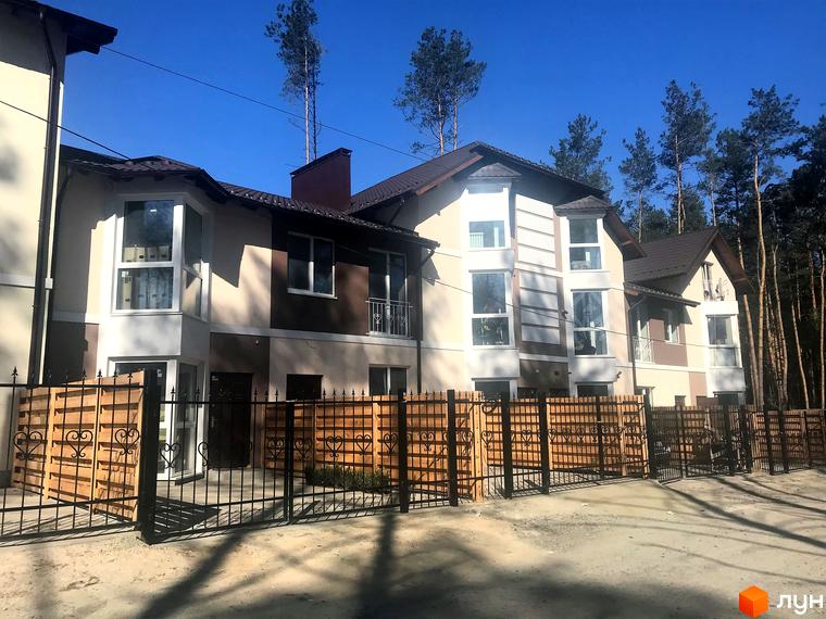 Котеджне містечко Сонячний 2. Зовнішній вигляд двоповерхових будинків з великими вікнами та дерев'яним парканом.