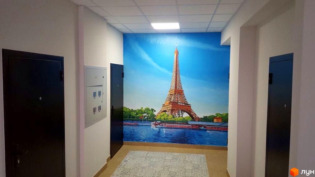 Інтер'єр коридору ЖК Comfort Club з фотошпалерами Ейфелевої вежі. На стінах двері та електричний щиток.