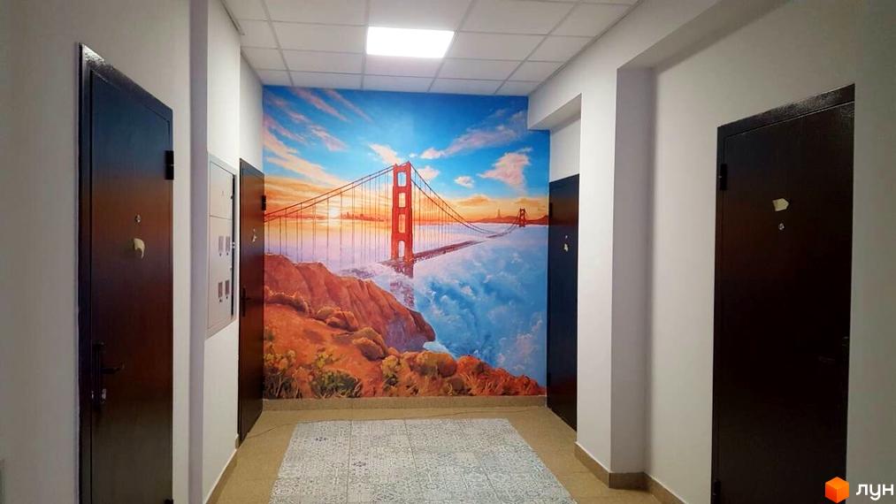 Комплекс Comfort Club: коридор з дверима та картиною із зображенням мосту Золоті Ворота. Яскравий дизайн стін створює атмосферу подорожі.