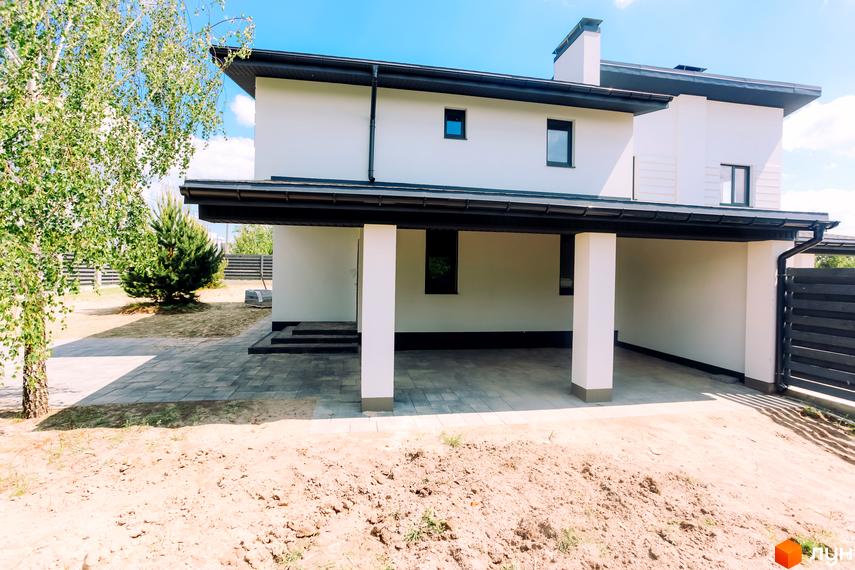 Білий дуплекс White Villages з навісом для авто. Навколо будинку – бруківка, дерева та паркан.