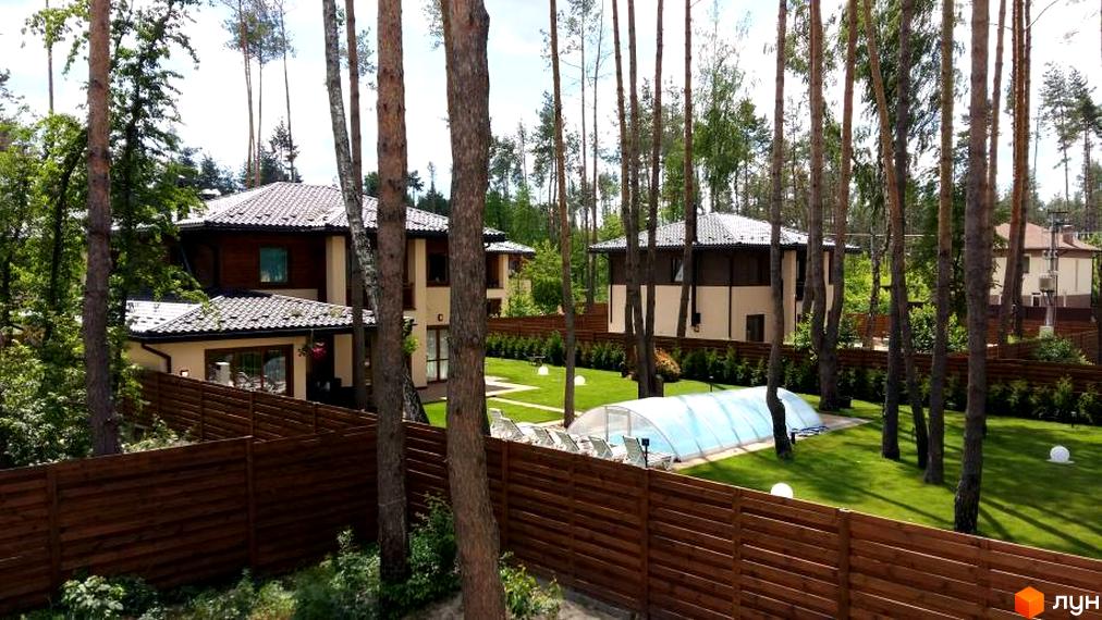 Котеджне містечко Віта Паркова. Сучасні будинки з білою штукатуркою та коричневими елементами, великі вікна, черепичні дахи. На території доглянутий газон, дерев'яний паркан та критий басейн.