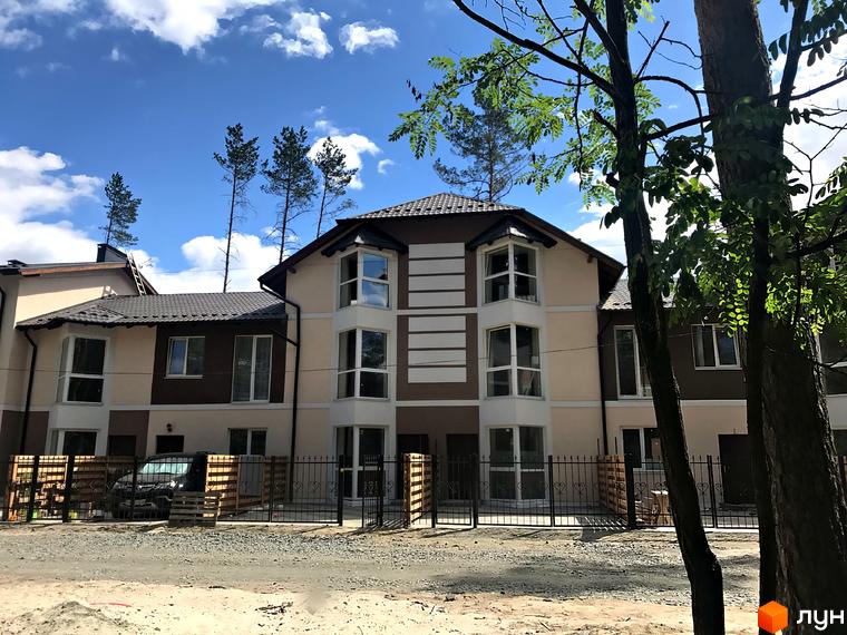 Котеджне містечко КМ Сонячний 2: двоповерхові будинки з великими вікнами та коричневим дахом. Прибудинкова територія огороджена парканом, видно автомобіль.