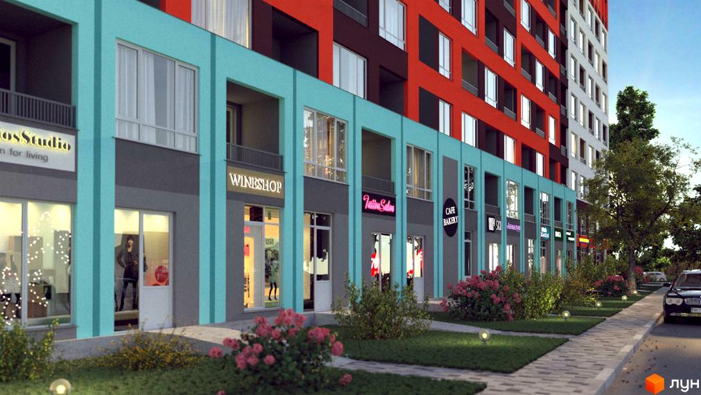 Новобудова ЖК А12 на Симоненка з фасадом з блакитних та червоних елементів. Прибудинкова територія з газоном, кущами та доріжкою.