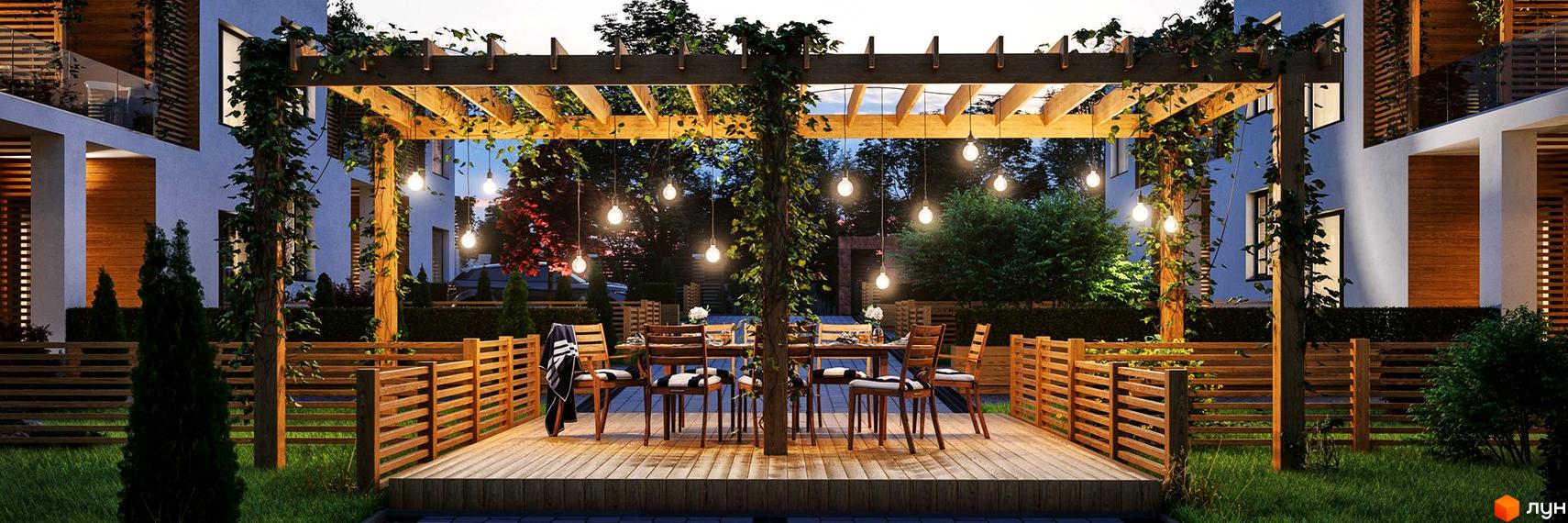 Котеджне містечко Golden Hills: будівлі зі світло-блакитними фасадами та дерев'яними елементами. Тераса з перголою та освітленням, оточена парканом і зеленню.