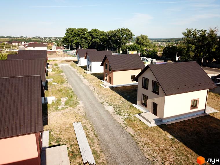 Котеджне містечко Green House: вид на нові будинки з коричневими дахами та прибудинкову територію з гравійною дорогою. Фотографія житлового комплексу.